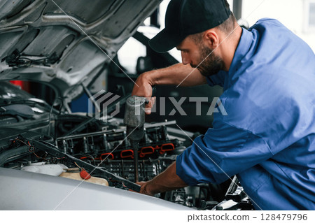 Adjusting the screws. Auto mechanic working in garage. Repair service Adjusting the screws. Auto mechanic working in garage. Repair service 128479796