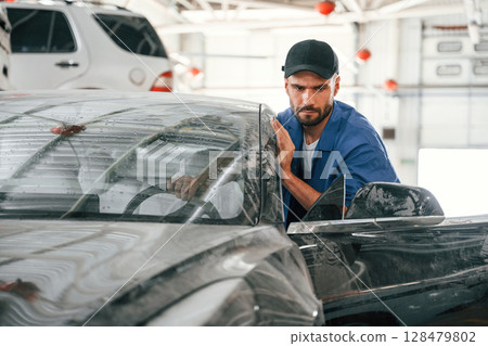 Dirty car is moved by auto mechanic that is in garage. Repair service 128479802
