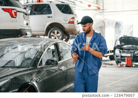 Near the dirty car. Auto mechanic working in garage. Repair service 128479807