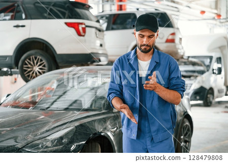 Near the dirty car. Auto mechanic working in garage. Repair service Near the dirty car. Auto mechanic working in garage. Repair service 128479808