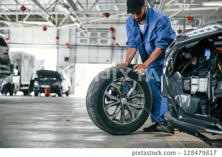 New tire, moving it. Auto mechanic working in garage. Repair service 128479817