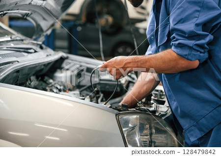 Adjusts the cable. Auto mechanic working in garage. Repair service 128479842