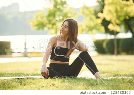 In black sportive clothes. Beautiful young woman is in the park at sunny daytime In black sportive clothes. Beautiful young woman is in the park at sunny daytime 128480363