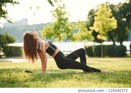 Side view, on the hands. Beautiful young woman in sportive clothes is in the park at sunny daytime 128480372