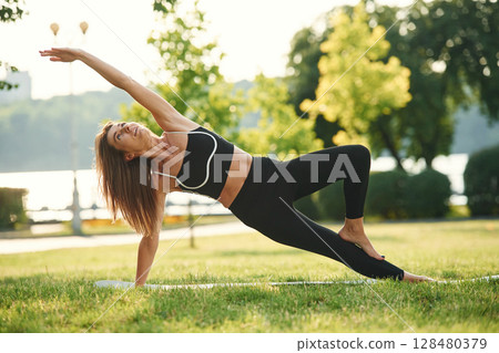 On the right hand and leg. Beautiful young woman in sportive clothes is in the park at sunny daytime 128480379