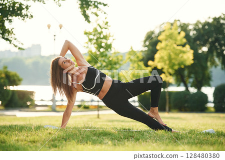 On the right hand and leg. Beautiful young woman in sportive clothes is in the park at sunny daytime On the right hand and leg. Beautiful young woman in sportive clothes is in the park at sunny daytime 128480380