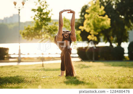Muscular arms. Beautiful young woman in sportive clothes is in the park at sunny daytime Muscular arms. Beautiful young woman in sportive clothes is in the park at sunny daytime 128480476