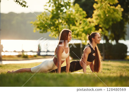 Conception of sport. Two women are doing exercises outdoors on the field 128480569