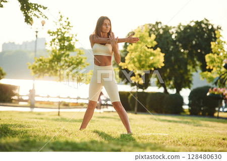 White sportive clothes. Beautiful young woman is in the park at sunny daytime White sportive clothes. Beautiful young woman is in the park at sunny daytime 128480630