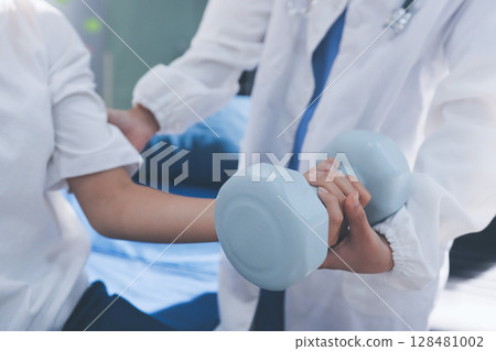 Unrecognizable uses blue hand weight during physical therapy session Unrecognizable uses blue hand weight during physical therapy session 128481002