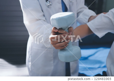 Unrecognizable uses blue hand weight during physical therapy session 128481003