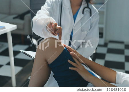 Female doctor hands doing physical therapy By extending the leg and knee of a male patient 128481018