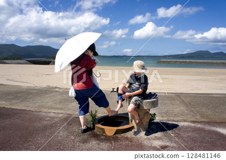 <Material> Parents and children washing their feet at the beach in summer 128481146