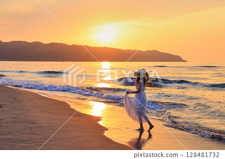 夕陽下在沙灘上散步的女人 128481732