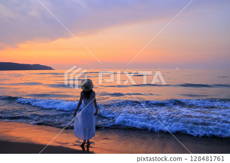 Woman walking on the beach at sunset 128481761