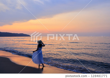 夕陽下在沙灘上散步的女人 夕陽下在沙灘上散步的女人 128481771