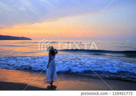 夕陽下在沙灘上散步的女人 夕陽下在沙灘上散步的女人 128481772