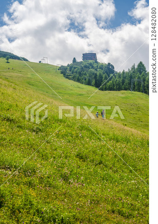 Hikers Ascending Sunny Green Hill Under Blue Sky with Clouds in Summer Landscape. High quality photo Hikers Ascending Sunny Green Hill Under Blue Sky with Clouds in Summer Landscape. High quality photo 128482080