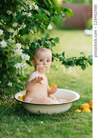 Baby Sitting In Basin Holding Lemon 128482980