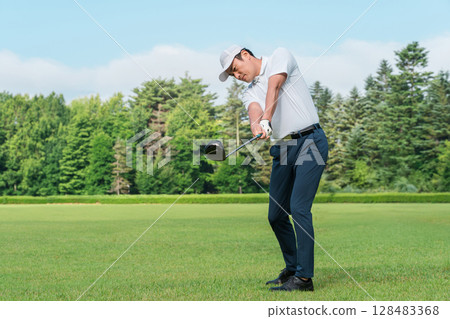 A golfer man playing golf at a golf course (smile, tee shot, golf competition) A golfer man playing golf at a golf course (smile, tee shot, golf competition) 128483368