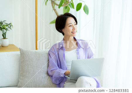 Middle-aged woman using a laptop in her room Middle-aged woman using a laptop in her room 128483381