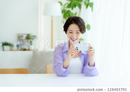 Middle woman operating a smartphone in the room 128483791