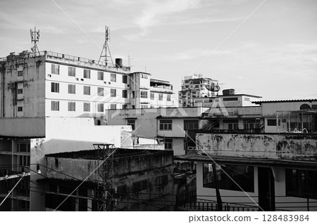 Monochrome photo of dense, aged city structures with rooftop details and strong contrasts 128483984