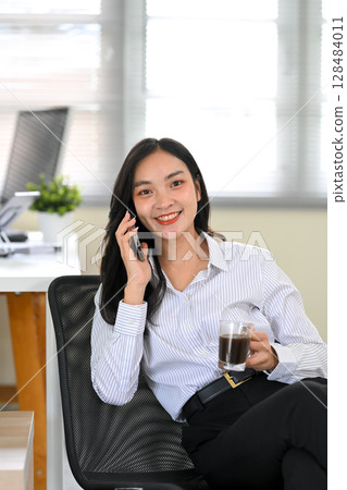 Happy businesswoman talking on the phone during a coffee break Happy businesswoman talking on the phone during a coffee break 128484011