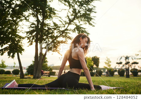 Sitting on twine. Beautiful young woman in sportive clothes is in the park at sunny daytime Sitting on twine. Beautiful young woman in sportive clothes is in the park at sunny daytime 128484052