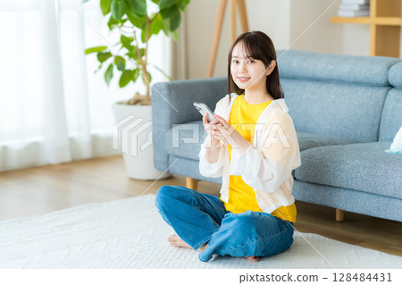 在房間裡操作智慧型手機的年輕女子 128484431