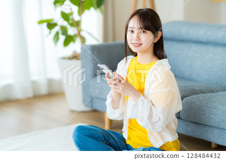 在房間裡操作智慧型手機的年輕女子 128484432