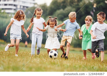 Playing soccer. Kids are having fun on the field at daytime together Playing soccer. Kids are having fun on the field at daytime together 128484867