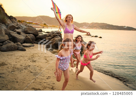 Joyful family playing together at the beach during sunset 128485005