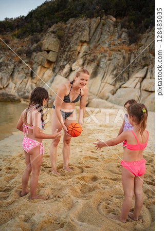 Family fun at the beach with kids playing basketball by the shore 128485035