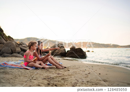 Joyful family moments shared on a sandy beach at sunset Joyful family moments shared on a sandy beach at sunset 128485050