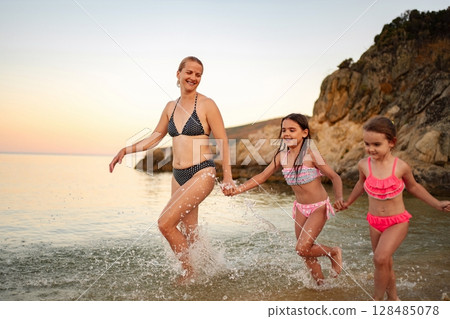 Joyful family bonding at the beach during a sunset stroll Joyful family bonding at the beach during a sunset stroll 128485078