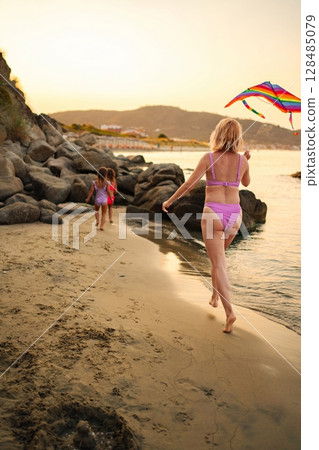 Family bonding time on the beach with colorful kite fun at sunset 128485079