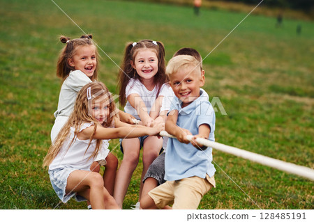 Game of strength. Tug of war game. Kids are having fun on the field at daytime together 128485191