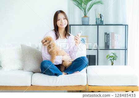 Young woman relaxing with her pet in her room 128485433