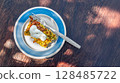 Delicious vegetable casserole topped with sour cream rests on a plate outdoors, showcasing vibrant colors in natural light 128485722