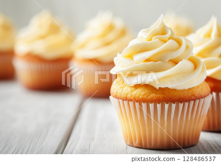 Vanilla Cupcakes topped with creamy sweet frosting treat. Tempting display of freshly baked cupcakes with white rich buttercream on top. Space for text. Close-up view. Seasonal celebrations. Birthday 128486537