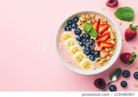 Colorful Smoothie Bowl with Fresh Fruits for a Healthy Breakfast. Pink berry smoothie bowl topped with fresh strawberries, bananas, blueberries, and crunchy granola. Above view, bright background. 128486967