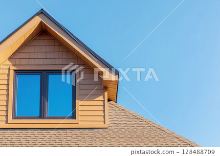House Exterior. Roof Window. Second floor among blue sky. Mansard attic. Newly build houses. Gable roof with skylight, asphalt roofing, shingles. Residential Home. Vinyl Siding. Polymeric roof-tiles 128488709