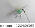 Cleaning the ceiling fan light with a duster 128489365
