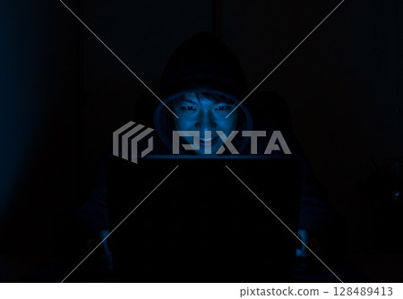 一名男子坐在黑暗房間的電腦前，在社群媒體上發布虛假訊息 128489413