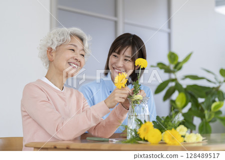 Senior woman and care staff enjoying flower arranging 128489517
