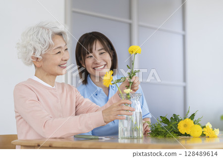 Senior woman and care staff enjoying flower arranging 128489614