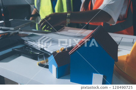 Closeup of team of industrial engineers meeting analyze machinery blueprints consult project on table in manufacturing factory. Working in manufacturing plant or production plant. Closeup of team of industrial engineers meeting analyze machinery blueprints consult project on table in manufacturing factory. Working in manufacturing plant or production plant. 128490725