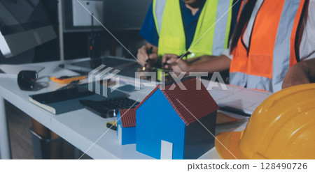 Closeup of team of industrial engineers meeting analyze machinery blueprints consult project on table in manufacturing factory. Working in manufacturing plant or production plant. Closeup of team of industrial engineers meeting analyze machinery blueprints consult project on table in manufacturing factory. Working in manufacturing plant or production plant. 128490726