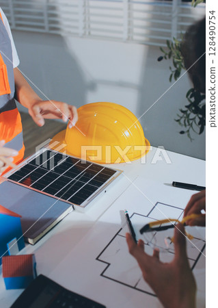 Closeup of team of industrial engineers meeting analyze machinery blueprints consult project on table in manufacturing factory. Working in manufacturing plant or production plant. 128490754